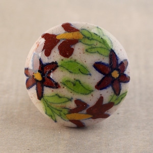 May include: White ceramic knob with a floral design. The knob features red, yellow, green, and blue flowers on a white background.