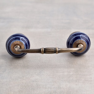 May include: A blue and white striped ceramic drawer pull with a brass arm.