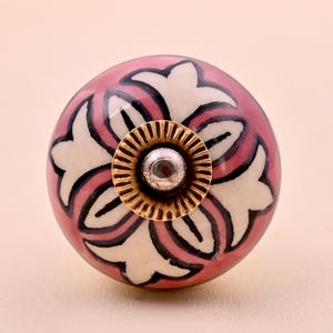 Handgemaakte roze, witte en zwarte keramische kastknop met bloemenmotief.