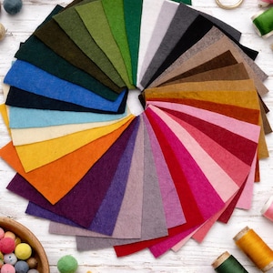May include: A collection of rectangular felt fabric swatches arranged in a circular fan pattern, featuring a wide spectrum of colours including greens, blues, yellows, oranges, purples, pinks, reds, browns, greys, black, and white.