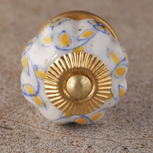 May include: White ceramic knob with a gold rim and a yellow and blue floral pattern.