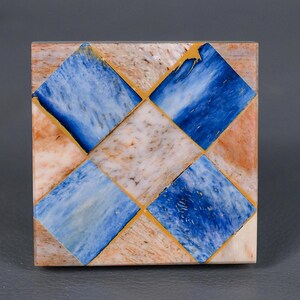 Puede incluir: Posavasos cuadrado con un patrón de cuadros de azulejos de mármol azul, blanco y marrón. Los azulejos están delineados en oro.