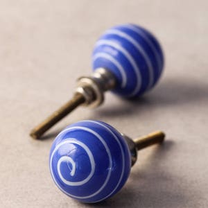 May include: Two blue and white ceramic cabinet knobs with a spiral design. The knobs have a silver metal base and a screw.