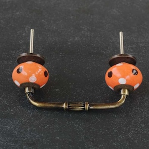 Può includere: Tiramaniglia per cassetto in ceramica arancione con pois bianchi e manico in ottone.