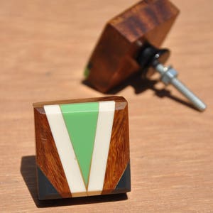 May include: Square wooden cabinet knob with a green, white and black geometric design.