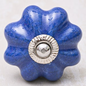 May include: A blue ceramic cabinet knob with a silver metal center. The knob is shaped like a flower with five petals.