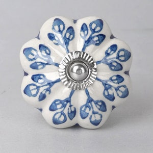 May include: A white ceramic knob with a blue floral design and a silver metal centre. The knob has a scalloped edge and is perfect for adding a touch of elegance to any room.
