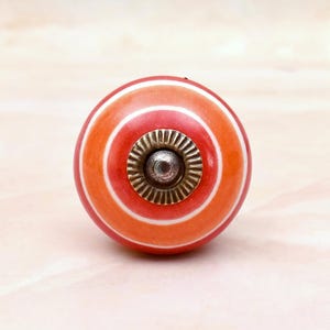 Pomello per mobile in ceramica fatto a mano con strisce concentriche arancioni e rosse.