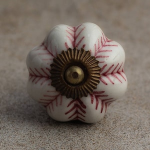May include: White ceramic cabinet knob with a red floral design and a gold metal base.