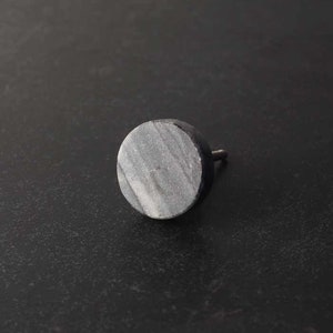 May include: A round, grey marble cabinet knob with a silver screw.