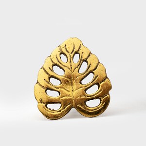 May include: Gold-toned metal leaf napkin ring with a cutout design.