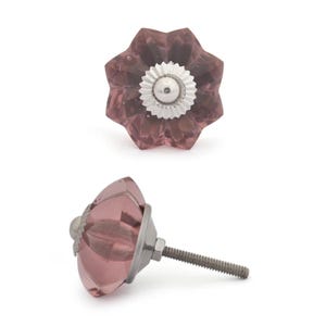 May include: Two decorative cabinet knobs. The knobs are a dusty rose colour with a flower-like design. Each knob has a silver-coloured metal base and screw. The knobs are designed for use on cabinets, drawers, or furniture.