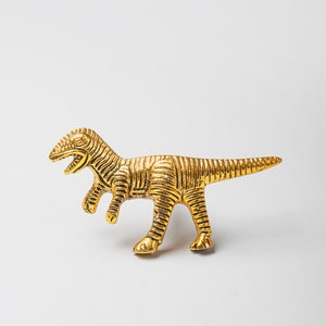 Peut inclure: Une figurine de dinosaure dorée avec une surface texturée.