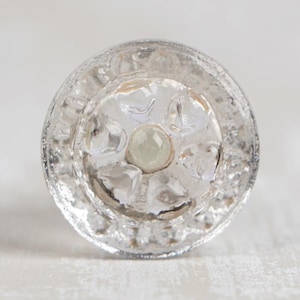 May include: Clear glass knob with a raised, textured design and a small, clear glass center.