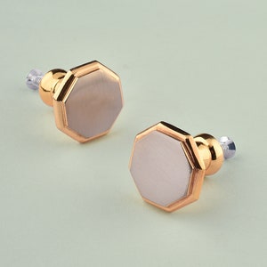May include: Two gold-toned hexagonal cabinet knobs with a brushed silver finish.