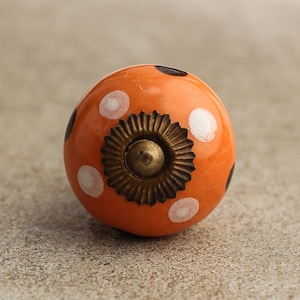 Può includere: Pomo in ceramica arancione con pois neri e bianchi. Il pomo ha una base in metallo dorato.