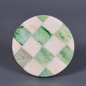 May include: Round coaster made of green and white checkered marble.