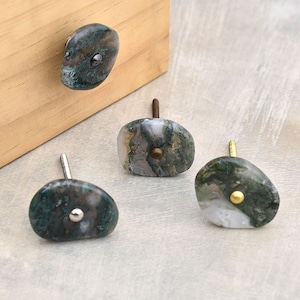 May include: Four agate stone cabinet knobs with different colored metal accents. The knobs are green, white, and gray with brown and black swirls. The metal accents are silver, gold, and brass.