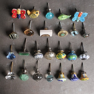 May include: Assortment of 24 colourful ceramic and glass cabinet knobs. The knobs feature various designs, including butterflies, birds, fish, geometric patterns, and floral motifs. The knobs are perfect for adding a touch of personality to any room.