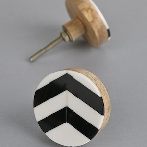 Könnte beinhalten: Runder Kabinettknauf mit einem schwarzen und weißen Chevron-Muster und einer Holzbasis.