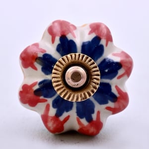 Tirador de cerámica hecho a mano con forma de flor en blanco, rojo y azul.