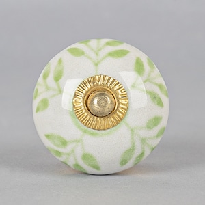 May include: White ceramic knob with a green leaf pattern and a gold metal center.