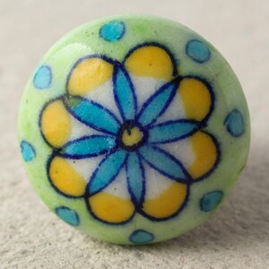 May include: A green ceramic knob with a blue and yellow floral design. The knob has a glossy finish and is ideal for adding a touch of colour to any room.
