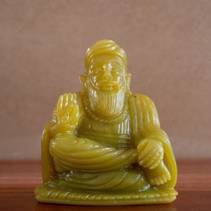 May include: A green jade statue of a seated Buddha with a serene expression. The statue is carved in detail and has a smooth, polished finish.