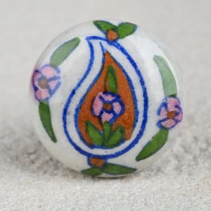 May include: A white ceramic knob with a blue and orange paisley design and pink flowers.