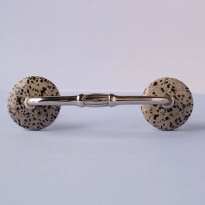 May include: A silver cabinet pull with two round, speckled, brown and black knobs.