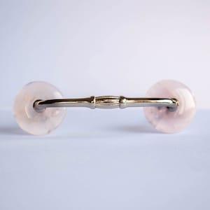 Op de afbeelding: Een zilveren ladegreep met twee ronde, doorschijnende roze handvatten.