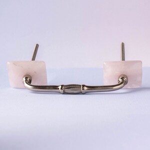 May include: A silver drawer pull with two square pink rose quartz knobs.