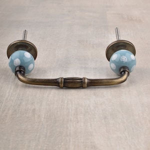 以下が含まれることがあります： 白い水玉模様の青いセラミックノブが真鍮製のプルハンドルに取り付けられています