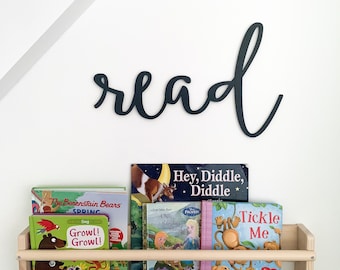 Op de afbeelding: Een houten boekenplank met een zwart metalen bord waarop "lezen" staat. De plank is gevuld met kinderboeken, waaronder "Hey, Diddle, Diddle", "The Berenstain Bears", "Growl! Growl!" en "Tickle Me".