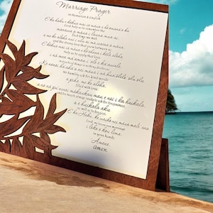 May include: A wooden sign with a carved design of leaves and a white background. The sign features a Hawaiian marriage prayer in both Hawaiian and English. The text reads: "E ka haku e kokua mai ia maua e he emana's ka Cord help us to remember the manawa a maua i launa mua ai. first time we met. a me ke aloha nui i ulu ai ma waena & тана. and the strong love that grow between us. E kikua mai ia maua e ho ohana i kila aloha i na mea ma amau i' ole e ka awale. Help us to apply that love in practical things so nothing divides us Ke nonoi ha aha a nei mana i na hua blelo olivolu We humbly ask for kind words a piha me ke aloha. filled with love. a ne na pu uwai makaukau mau e noi i i ka kuikala. and for hearts always ready to ask for forgiveness a e huikala aku as well as to forgive E ka Haku ke waiko nei maca male ana Cord, we leave out morriage i loke & kou lima. in your hands. Amene. Amen."