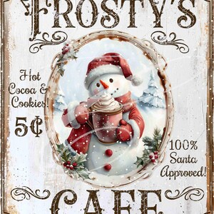 Pode incluir: Uma placa de estilo vintage para o Café Frosty's, com um boneco de neve segurando uma xícara de chocolate quente. A placa é branca com letras marrons e uma borda vermelha. O texto na placa diz "Frosty's Cafe", "Chocolate quente e biscoitos! 5¢", e "100% Aprovado pelo Papai Noel!"