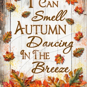 May include: A white wooden sign with the text "I can smell autumn dancing in the breeze" written in brown cursive lettering. The sign is decorated with colourful autumn leaves.