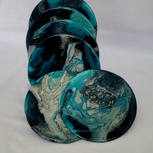 Puede incluir: Conjunto de seis posavasos redondos con patrones abstractos en espiral en tonos de turquesa, negro y blanco.