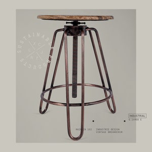 May include: A brown wooden top swivel bar stool with a metal base and a screw adjustment mechanism. The stool is made of metal and has a copper finish. The stool is labeled "INDUSTRIAL 0.14900 E" and "HAIRIN 102 INDUSTRIE DESIGN VINTAGE DREHHOCKER".