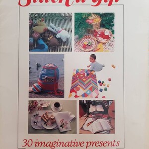 May include: A book cover with the title "Stitch a Gift" in red lettering. The cover features five images of handmade gifts, including a stuffed animal, a picnic basket, a backpack, a baby blanket, and a tea towel. The text below the images reads "30 imaginative presents to sew in next to no time."