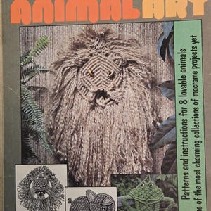 Puede incluir: Portada del libro "Macramé Animal Art" con un león de macramé con una melena desgreñada. La portada también muestra ilustraciones de un león, un cerdo y una rana. El libro promete patrones e instrucciones para 8 animales de macramé.