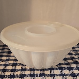 Puede incluir: Tazón de plástico blanco con un diseño acanalado y una tapa a juego. La tapa tiene una pequeña abertura en el centro.