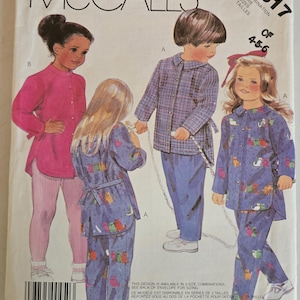 Op de afbeelding: McCall's naaipatroon-envelop met illustraties van kinderkleding. De omslag toont tekeningen van een meisje in een roze tuniek en legging, en kinderen in pyjama's. Het patroonnummer is 3317, maten 4-5-6.