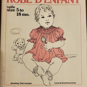 May include: A sewing pattern envelope for a baby dress titled BABY DRESS ROBE D'ENFANT. The cover features a line drawing of a child wearing a smocked dress, holding a rattle, with a teddy bear nearby. Text includes size 5 to 18 mo and Grace L. Knott.