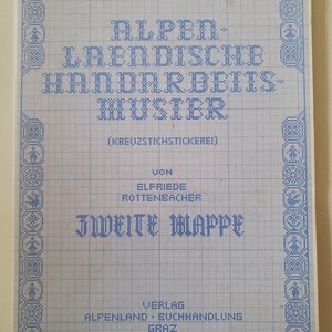 May include: A blue and white cover for a cross-stitch pattern book. The cover features the text "Alpen-Landische Handarbeits-Muster (Kreuzstichstickerei)" and "Zweite Mappe". The cover also includes the text "Von Elfriede Rottenbacher" and "Verlag Alpenland - Buchhandlung Graz".