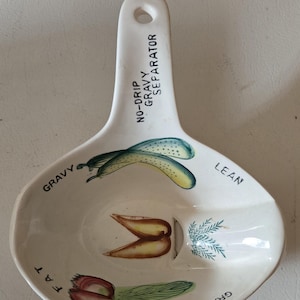 May include: White ceramic gravy separator with a handle that reads "No-Drip Gravy Separator". The separator has four sections labeled "Gravy", "Fat", "Lean", and "Gravy". Each section has a different vegetable illustration.