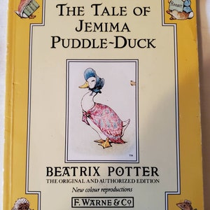 Può includere: Una copertina di libro gialla con il titolo "The Tale of Jemima Puddle-Duck" di Beatrix Potter. La copertina presenta illustrazioni di Jemima Puddle-Duck, Peter Rabbit e altri personaggi del libro.