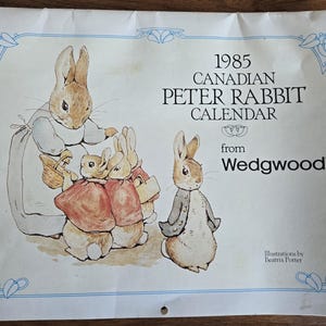 May include: A vintage 1985 Canadian Peter Rabbit calendar from Wedgwood. The illustration features Peter Rabbit and other rabbits in a classic storybook style, with a blue border and text.