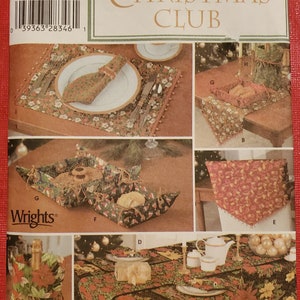 Op de afbeelding: Een naaipatroon voor een kerstclub met een tafelkleed, placemats, servetringen, een broodmand en een flesbeschermer. Het patroon is van Simplicity en is maat één.