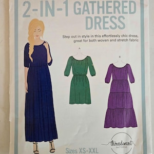 May include: A sewing pattern for a 2-in-1 gathered dress. The cover features a drawing of a woman in a navy blue dress, and illustrations of green and purple dresses. Text includes "2-IN-1 GATHERED DRESS" and "Sizes XS-XXL".